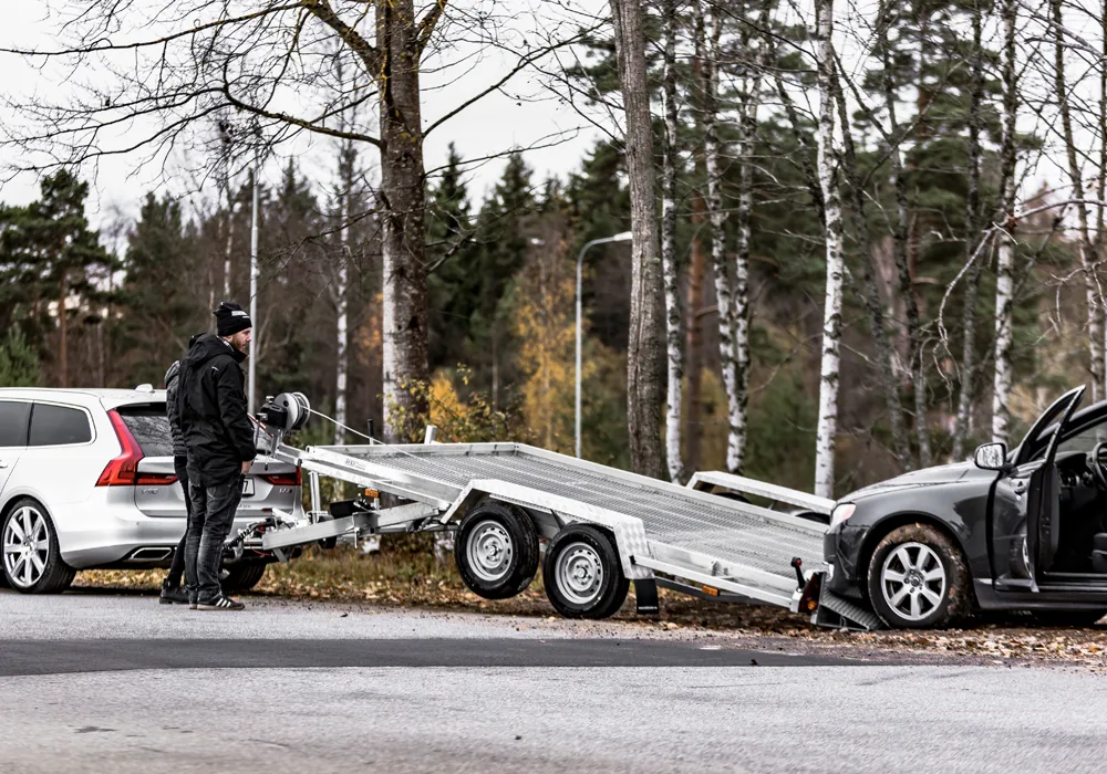 Bil som kör upp på ett bilsläp - ett fordonssläp gör transporten säker och smidig