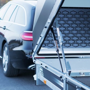 Ett öppet släp med kåpa med en bil framför